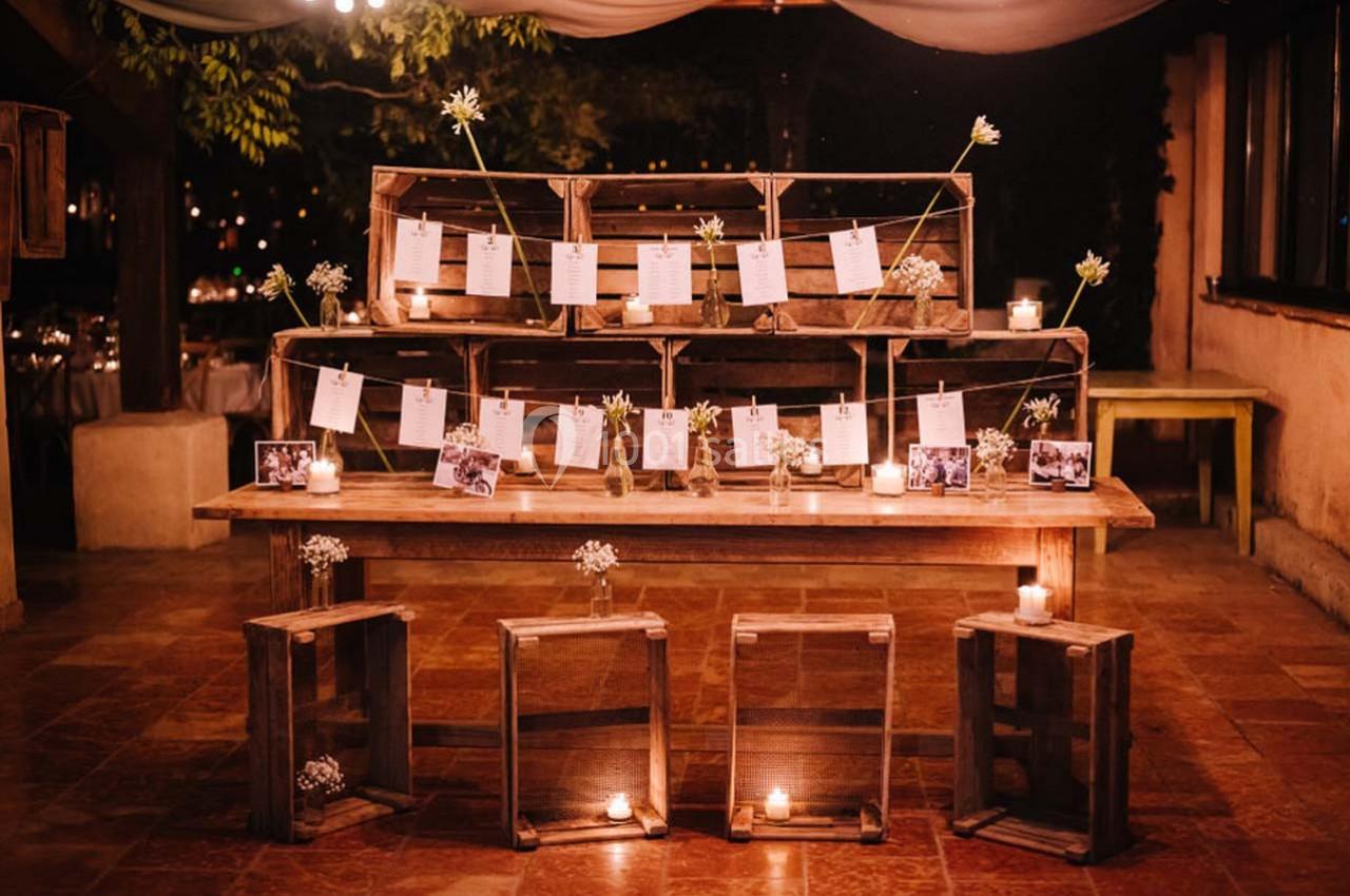 Location salle Gémenos (Bouches-du-Rhône) - Moulin de Gemenos #88 Décoration de mariage avec des caisses en bois, photos et bougies disposées sur une table dans une ambiance chaleureuse.