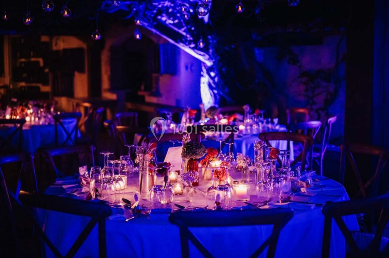 Location salle Gémenos (Bouches-du-Rhône) - Moulin de Gemenos #91 Table ronde décorée pour un dîner, éclairée par des bougies et des lumières violettes dans une ambiance nocturne.