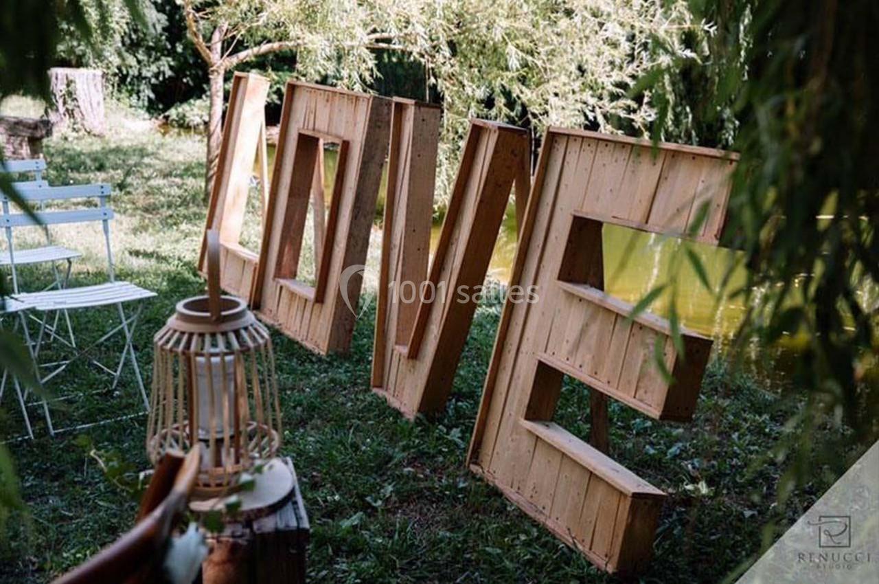 Location salle Gémenos (Bouches-du-Rhône) - Moulin de Gemenos #93 Grandes lettres en bois formant le mot ’LOVE’ disposées sur une pelouse près d'un étang, entourées de verdure.