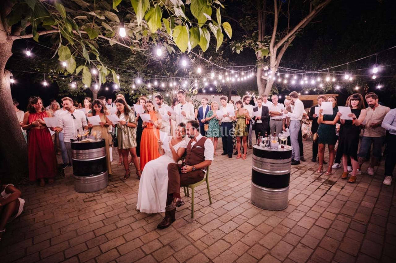 Location salle Gémenos (Bouches-du-Rhône) - Moulin de Gemenos #94 Groupe de personnes rassemblées en soirée extérieure sous des guirlandes lumineuses, certaines tenant des feuilles.