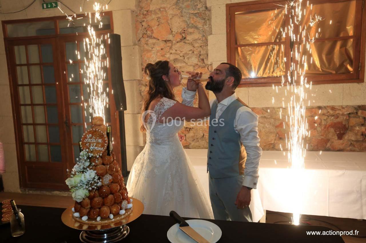 Location salle Gémenos (Bouches-du-Rhône) - Moulin de Gemenos #97 Un couple en tenue de mariage trinque devant une pièce montée, entouré d'étincelles festives.