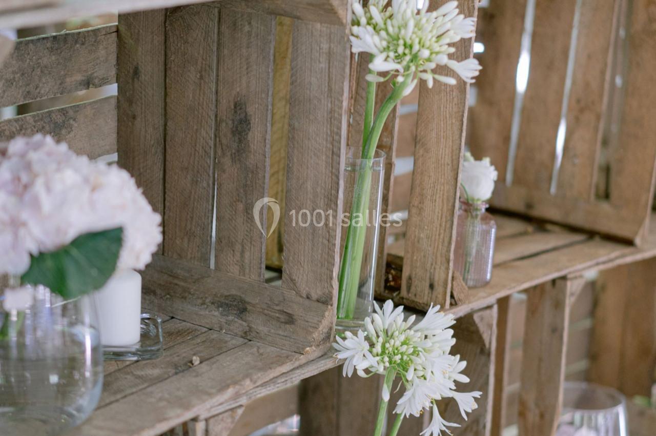 Location salle Gémenos (Bouches-du-Rhône) - Moulin de Gemenos #105 Des caisses en bois empilées contenant des vases avec des fleurs blanches et roses dans un décor rustique.