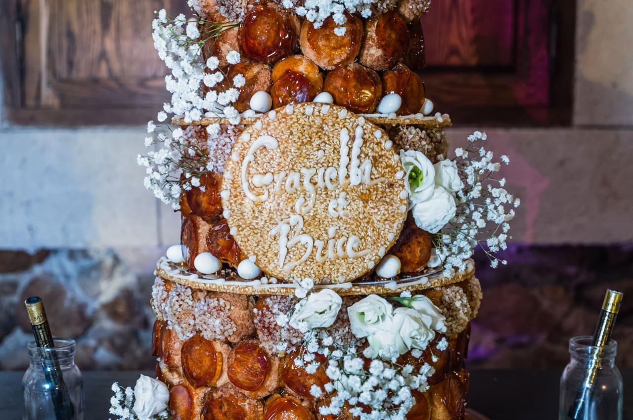 Location salle Gémenos (Bouches-du-Rhône) - Moulin de Gemenos #108 Pièce montée en choux décorée de fleurs blanches, de gypsophile et d'une plaque portant des prénoms.