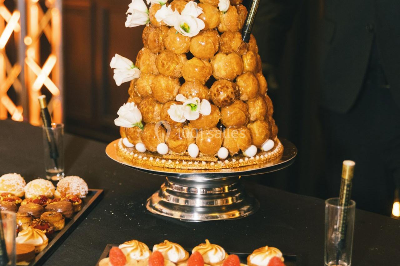 Location salle Gémenos (Bouches-du-Rhône) - Moulin de Gemenos #112 Pièce montée de choux décorée de fleurs blanches, présentée sur un plateau argenté lors d'un événement.