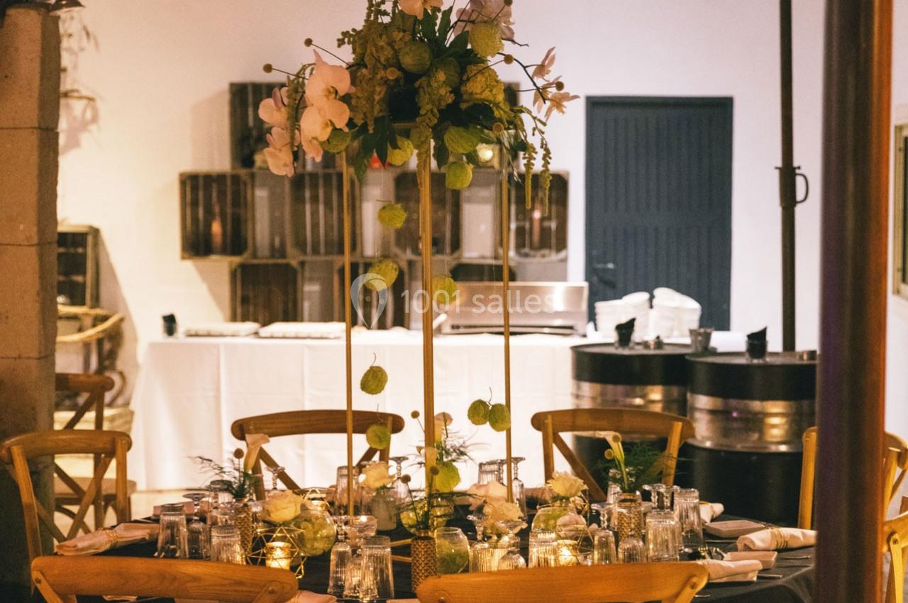 Location salle Gémenos (Bouches-du-Rhône) - Moulin de Gemenos #113 Table élégamment dressée avec un centre de table floral, entourée de chaises en bois dans une salle de réception.