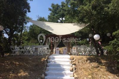 Miniature Location salle La Roquebrussanne (Var) - Les Arbousiers #15 Un couple en tenue de mariage coupe une pièce montée décorée, devant un mur en pierre.