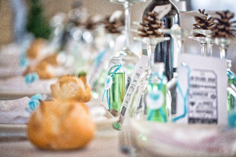 Location salle La Roquebrussanne (Var) - Les Arbousiers #32 Table décorée avec des bouteilles miniatures, des pommes de pin et des pains individuels pour un repas festif.