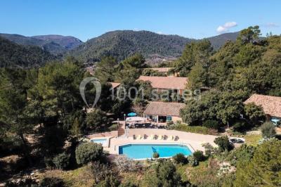 Miniature Location salle La Roquebrussanne (Var) - Les Arbousiers #1 Un couple en tenue de mariage coupe une pièce montée décorée, devant un mur en pierre.