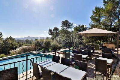 Miniature Location salle La Roquebrussanne (Var) - Les Arbousiers #33 Un couple en tenue de mariage coupe une pièce montée décorée, devant un mur en pierre.
