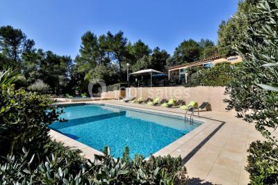 Miniature Location salle La Roquebrussanne (Var) - Les Arbousiers #17 Un couple en tenue de mariage coupe une pièce montée décorée, devant un mur en pierre.