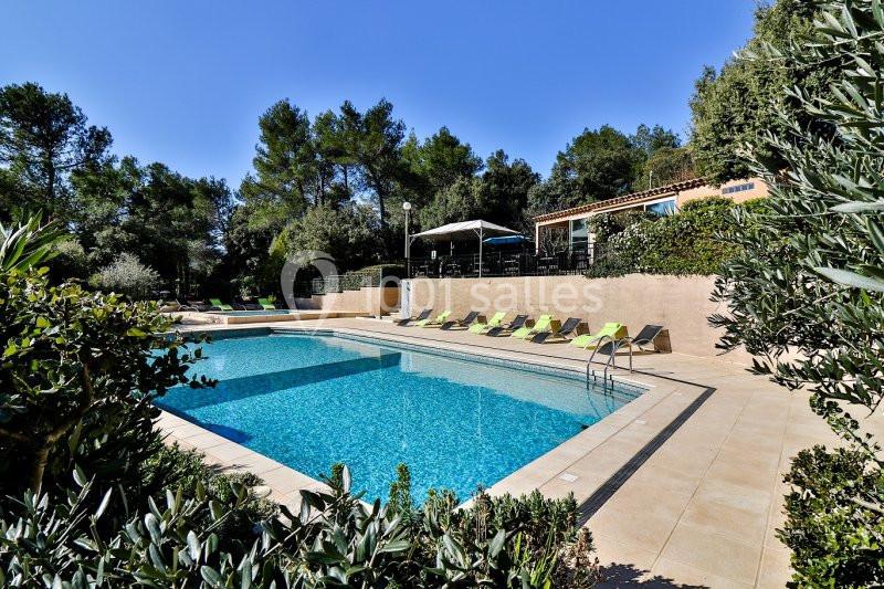 Location salle La Roquebrussanne (Var) - Les Arbousiers #17 Piscine extérieure entourée de chaises longues, végétation et maison en arrière-plan sous un ciel dégagé.