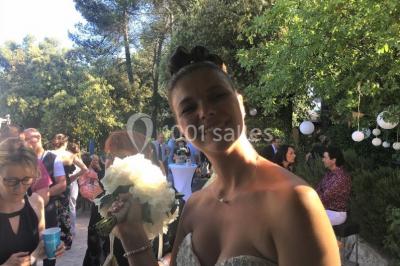 Miniature Location salle La Roquebrussanne (Var) - Les Arbousiers #25 Un couple en tenue de mariage coupe une pièce montée décorée, devant un mur en pierre.