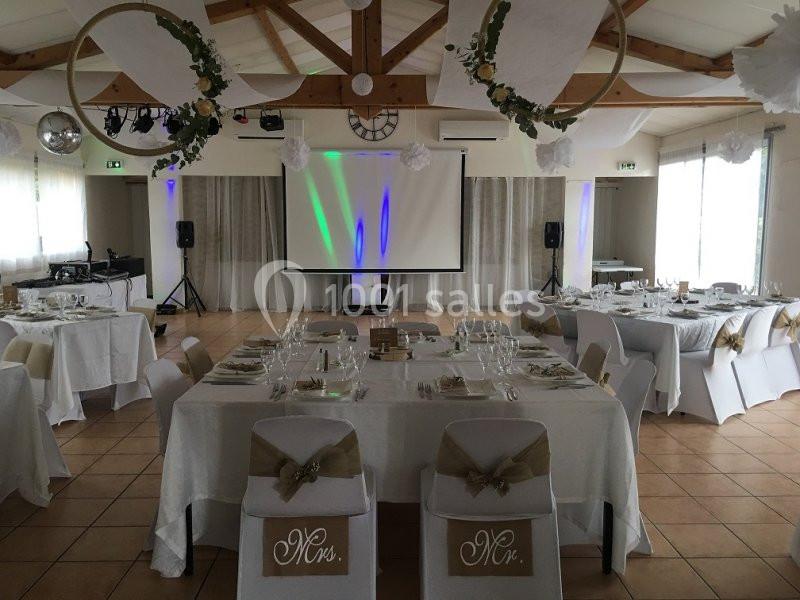 Location salle La Roquebrussanne (Var) - Les Arbousiers #29 Salle de réception décorée pour un mariage, avec tables dressées, chaises ornées et écran de projection en fond.