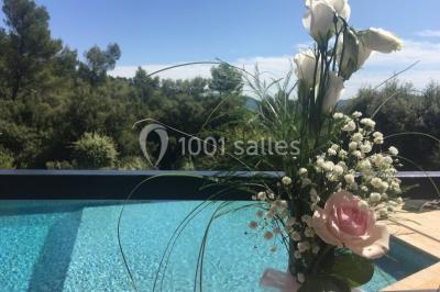 Miniature Location salle La Roquebrussanne (Var) - Les Arbousiers #23 Un couple en tenue de mariage coupe une pièce montée décorée, devant un mur en pierre.