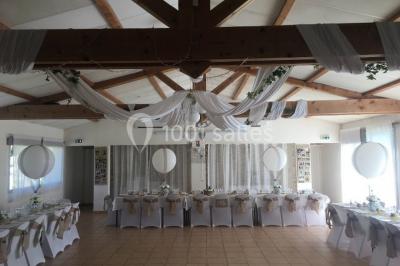 Miniature Location salle La Roquebrussanne (Var) - Les Arbousiers #28 Un couple en tenue de mariage coupe une pièce montée décorée, devant un mur en pierre.