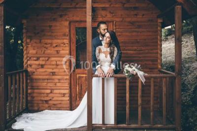 Miniature Location salle La Roquebrussanne (Var) - Les Arbousiers #2 Un couple en tenue de mariage coupe une pièce montée décorée, devant un mur en pierre.