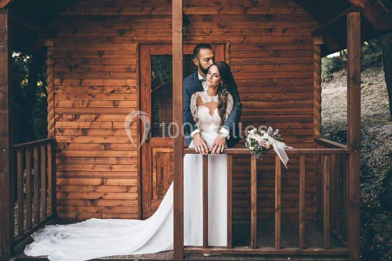 Location salle La Roquebrussanne (Var) - Les Arbousiers #2 Un couple en tenue de mariage pose sur la terrasse en bois d'une petite cabane entourée de nature.