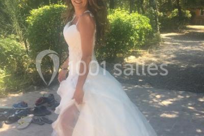 Miniature Location salle La Roquebrussanne (Var) - Les Arbousiers #31 Un couple en tenue de mariage coupe une pièce montée décorée, devant un mur en pierre.