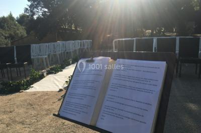Miniature Location salle La Roquebrussanne (Var) - Les Arbousiers #26 Un couple en tenue de mariage coupe une pièce montée décorée, devant un mur en pierre.