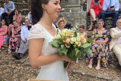 Miniature Location salle La Roquebrussanne (Var) - Les Arbousiers #16 Un couple en tenue de mariage coupe une pièce montée décorée, devant un mur en pierre.