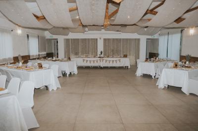 Miniature Location salle La Roquebrussanne (Var) - Les Arbousiers #40 Un couple en tenue de mariage coupe une pièce montée décorée, devant un mur en pierre.