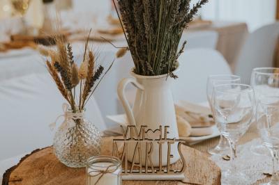 Miniature Location salle La Roquebrussanne (Var) - Les Arbousiers #41 Un couple en tenue de mariage coupe une pièce montée décorée, devant un mur en pierre.