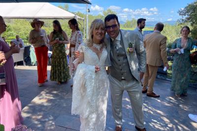 Miniature Location salle La Roquebrussanne (Var) - Les Arbousiers #13 Un couple en tenue de mariage coupe une pièce montée décorée, devant un mur en pierre.