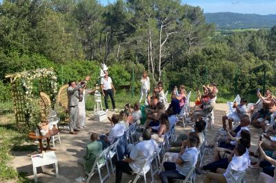 Miniature Location salle La Roquebrussanne (Var) - Les Arbousiers #9 Un couple en tenue de mariage coupe une pièce montée décorée, devant un mur en pierre.