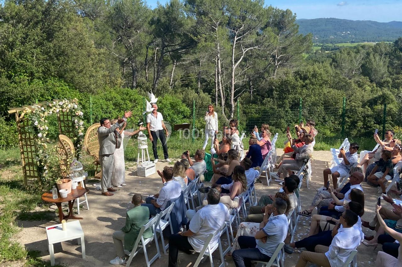 Location salle La Roquebrussanne (Var) - Les Arbousiers #9 Cérémonie en plein air avec des invités assis, un officiant et un couple debout, entourés de végétation.