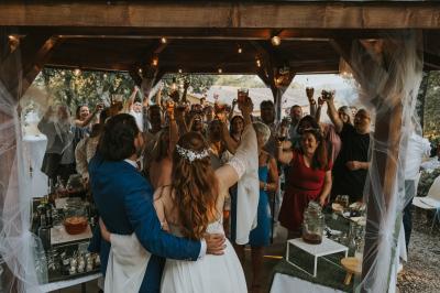 Miniature Location salle La Roquebrussanne (Var) - Les Arbousiers #10 Un couple en tenue de mariage coupe une pièce montée décorée, devant un mur en pierre.