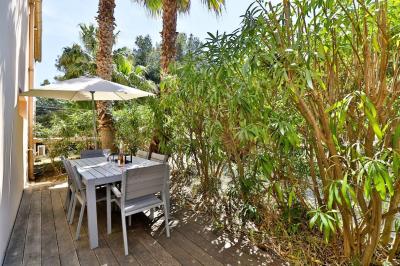 Table dressée avec assiettes en céramique, serviettes vertes pliées, couverts dorés, verres et décoration florale blanche.