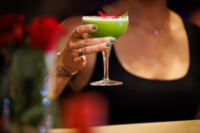 Table dressée avec assiettes en céramique, serviettes vertes pliées, couverts dorés, verres et décoration florale blanche.