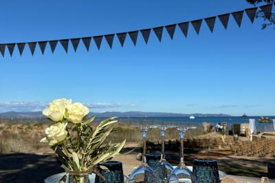 Table dressée avec assiettes en céramique, serviettes vertes pliées, couverts dorés, verres et décoration florale blanche.