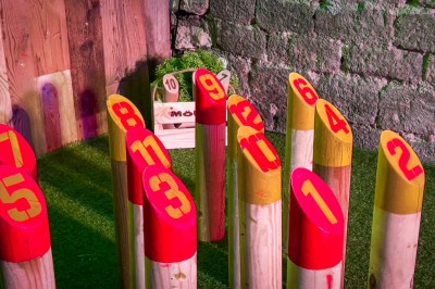 Miniature Location salle Paris 4 (Paris) - Paris Clandestin #9 Fléchettes colorées dans une caisse en bois au premier plan, cible de jeu accrochée sur un mur en pierre en arrière-plan.