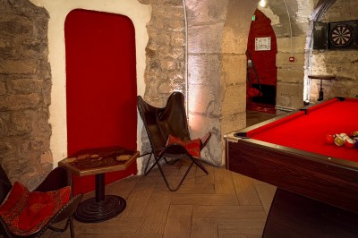 Miniature Location salle Paris 4 (Paris) - Paris Clandestin #11 Fléchettes colorées dans une caisse en bois au premier plan, cible de jeu accrochée sur un mur en pierre en arrière-plan.