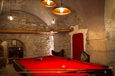 Miniature Location salle Paris 4 (Paris) - Paris Clandestin #14 Fléchettes colorées dans une caisse en bois au premier plan, cible de jeu accrochée sur un mur en pierre en arrière-plan.