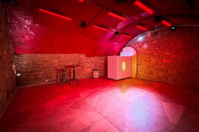 Miniature Location salle Paris 4 (Paris) - Paris Clandestin #16 Fléchettes colorées dans une caisse en bois au premier plan, cible de jeu accrochée sur un mur en pierre en arrière-plan.