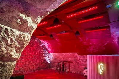 Miniature Location salle Paris 4 (Paris) - Paris Clandestin #18 Fléchettes colorées dans une caisse en bois au premier plan, cible de jeu accrochée sur un mur en pierre en arrière-plan.