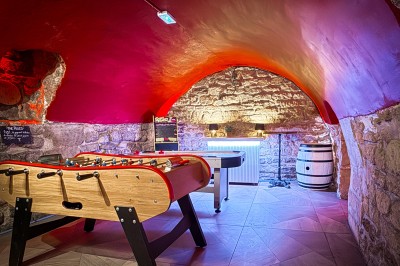 Miniature Location salle Paris 4 (Paris) - Paris Clandestin #19 Fléchettes colorées dans une caisse en bois au premier plan, cible de jeu accrochée sur un mur en pierre en arrière-plan.