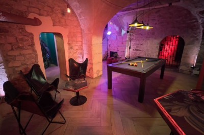 Miniature Location salle Paris 4 (Paris) - Paris Clandestin #29 Fléchettes colorées dans une caisse en bois au premier plan, cible de jeu accrochée sur un mur en pierre en arrière-plan.