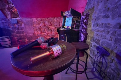 Miniature Location salle Paris 4 (Paris) - Paris Clandestin #30 Fléchettes colorées dans une caisse en bois au premier plan, cible de jeu accrochée sur un mur en pierre en arrière-plan.