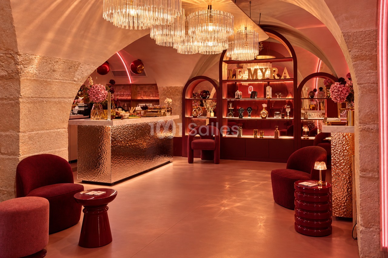 Espace de réception en sous-sol voûté aux tons bordeaux et dorés, avec lustres en cristal, bar en métal martelé doré et fauteuils velours bordeaux.