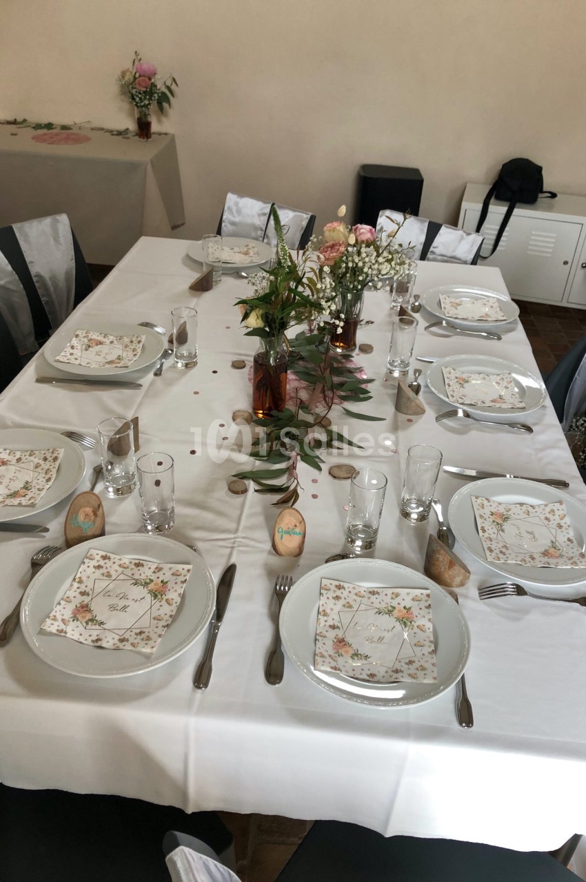 Table dressée pour un repas, décorée avec des fleurs, des menus imprimés et des marque-places personnalisés.