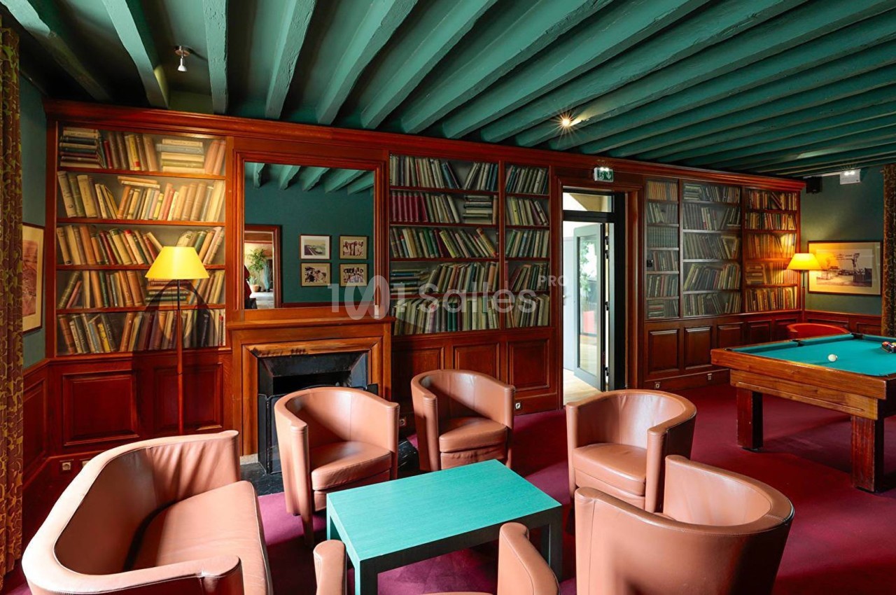Salle avec des étagères remplies de livres, un billard, des fauteuils en cuir et un plafond peint en vert.