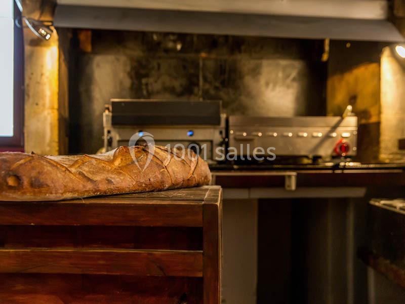 Location salle Bordeaux (Gironde) - Restaurant Le Family #31 Baguette de pain posée sur un comptoir en bois, avec un four professionnel en arrière-plan dans une cuisine.
