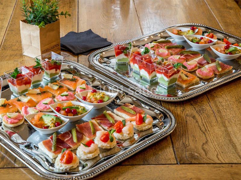Location salle Bordeaux (Gironde) - Restaurant Le Family #22 Plateaux de canapés variés avec légumes, saumon, jambon et verrines colorées, disposés sur une table en bois.