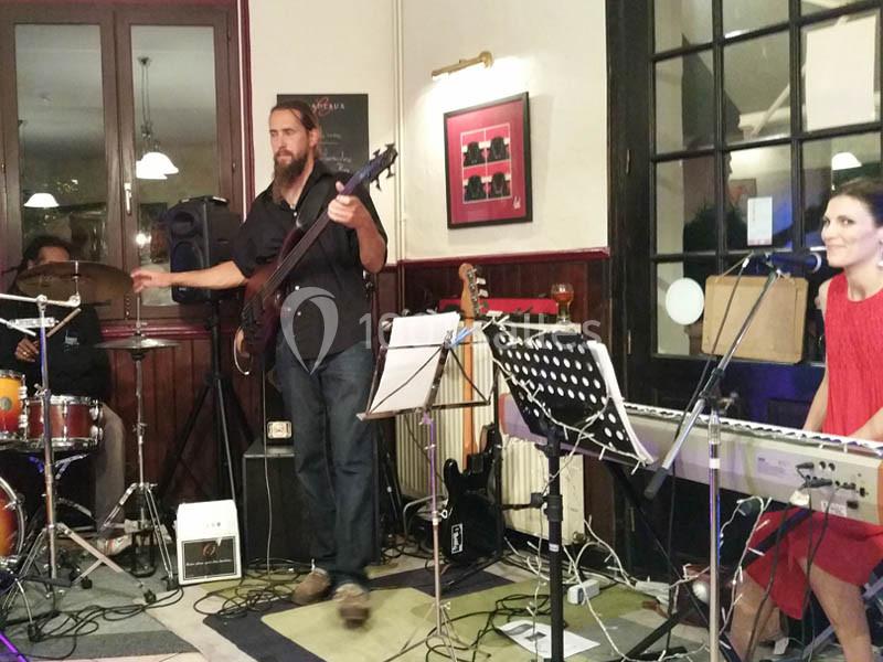 Location salle Bordeaux (Gironde) - Restaurant Le Family #27 Un groupe de musiciens joue en intérieur, avec un bassiste, une pianiste-chanteuse et un batteur.