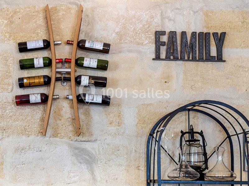 Location salle Bordeaux (Gironde) - Restaurant Le Family #5 Porte-bouteilles mural en bois avec plusieurs bouteilles de vin, décoré d'une inscription ’Family’ sur un mur en pierre.