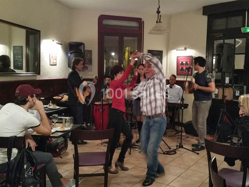 Location salle Bordeaux (Gironde) - Restaurant Le Family #29 Des personnes dansent au centre d'un café animé, avec un groupe de musiciens jouant en arrière-plan.