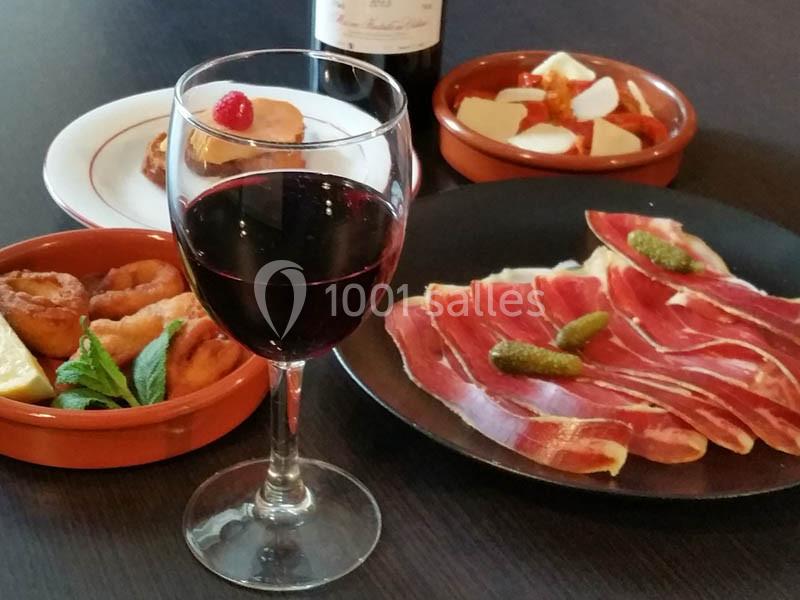 Location salle Bordeaux (Gironde) - Restaurant Le Family #25 Assiette de jambon cru, tapas variées et verre de vin rouge sur une table sombre.